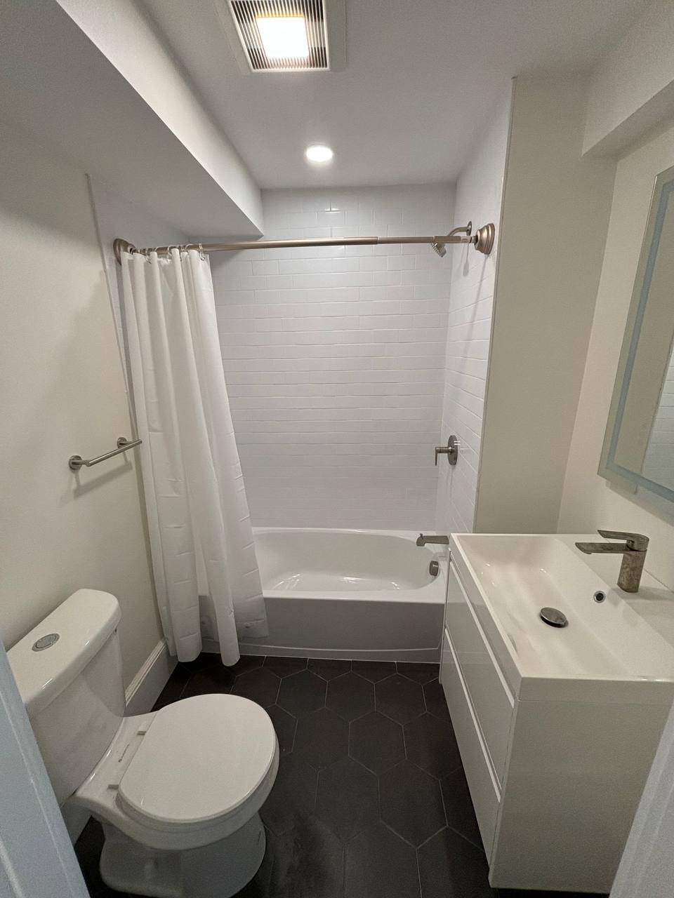 Bathroom with alcove tub, white subway tile, toilet and wall-mounted vanity