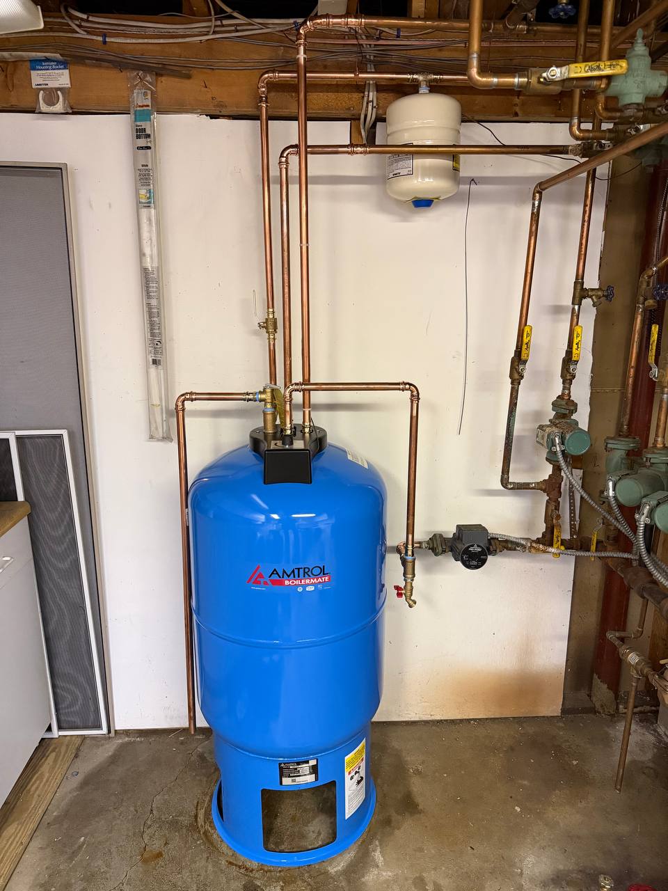 Blue indirect water heater tank with copper piping and circulator pump in a basement
