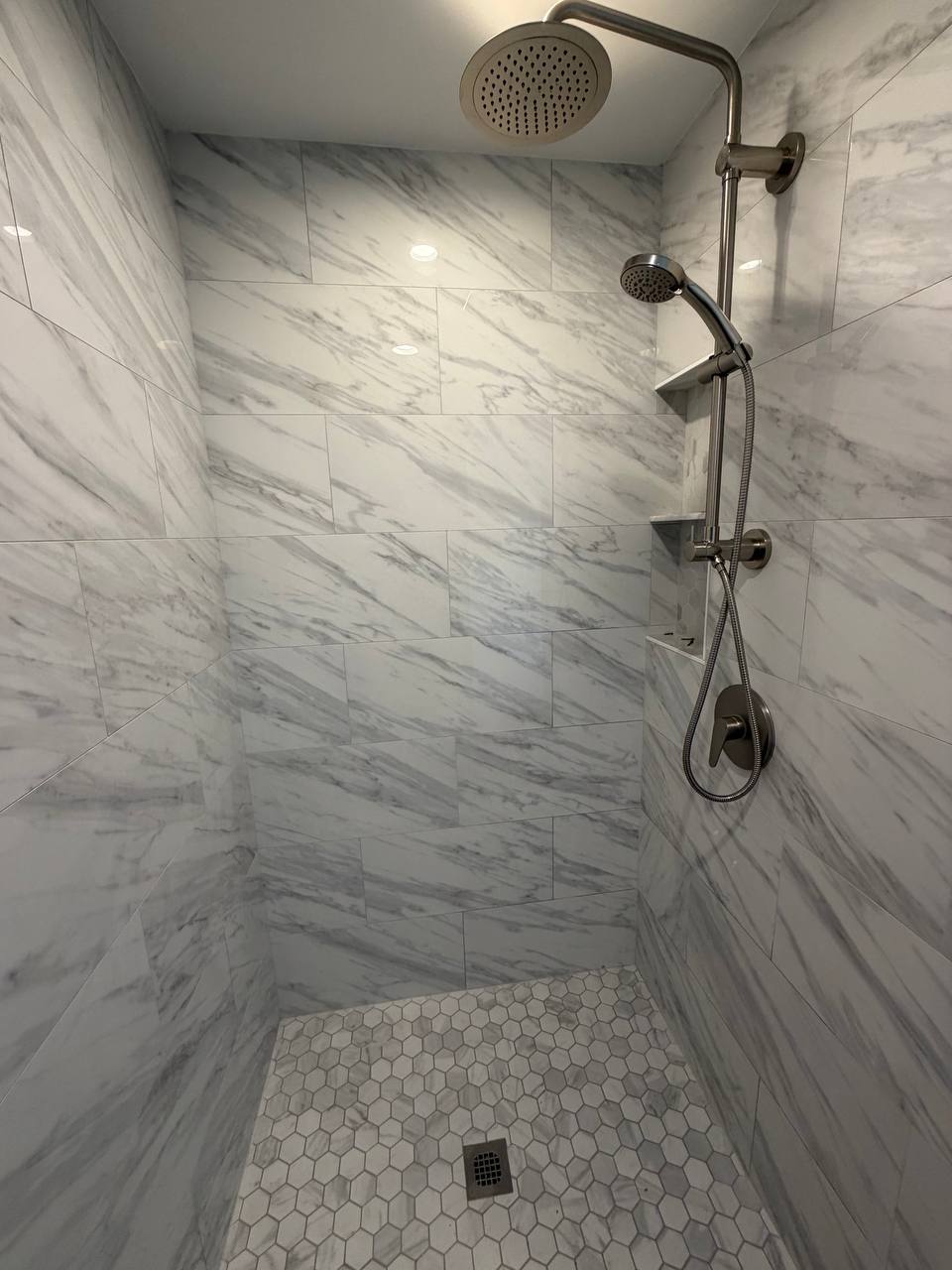 Walk-in tiled shower with rainfall and handheld showerheads and hexagon mosaic floor